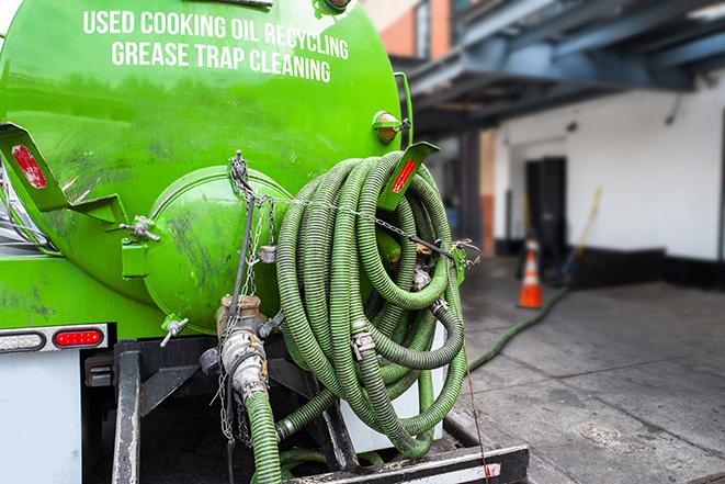 a technician pumping a grease trap in a commercial building in Astor